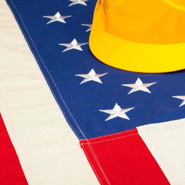 Casco de construcción tendido sobre nosotros bandera - concepto de la industria de construcción —  Fotos de Stock