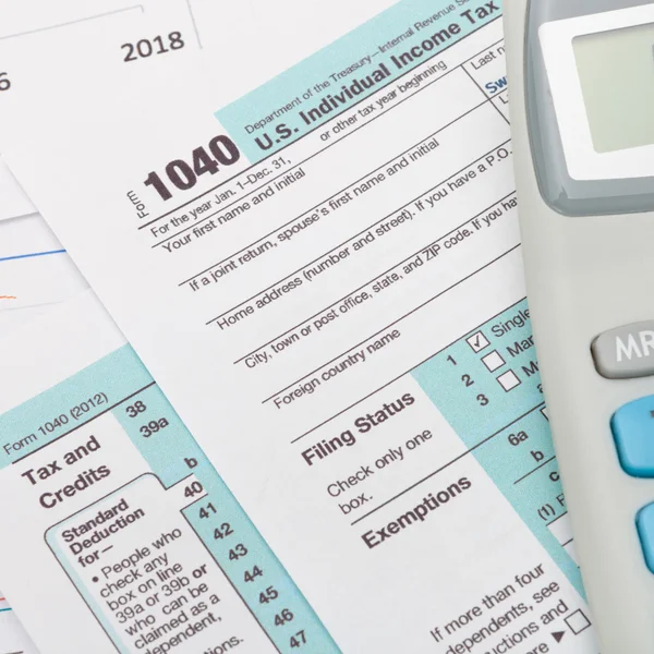 US 1040 Tax Form and calculator over it - studio shot — Stock Photo, Image