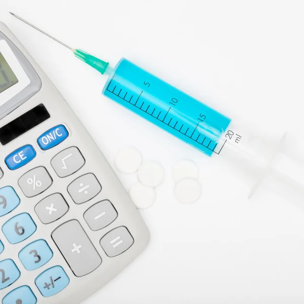 Syringe with blue liquid inside and calculator — Stock Photo, Image