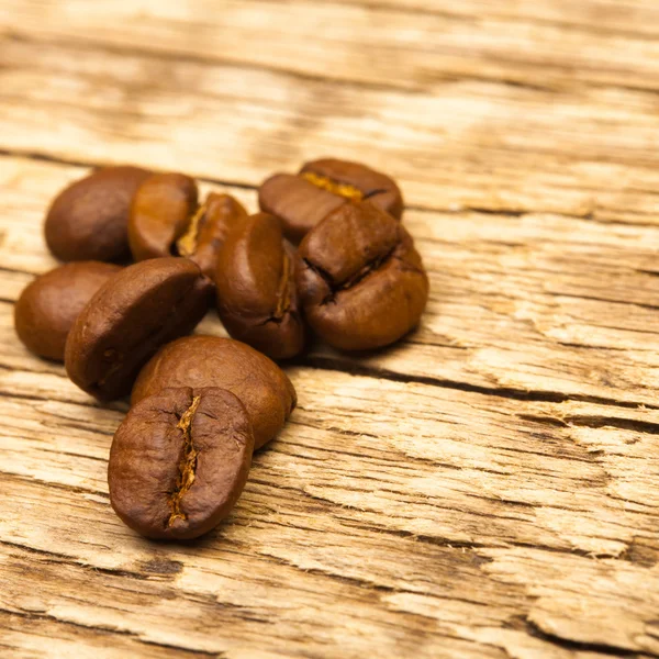 Roasted coffee beans on old wooden table - close up studio shot — Stock Photo, Image