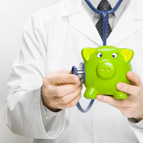 Doctor checking piggybank with help of stethoscope — Stock Photo, Image