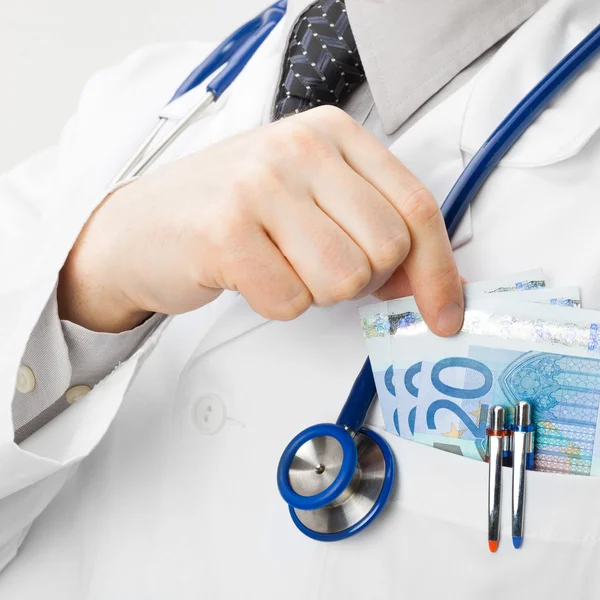 Medical doctor with money in his pocket - closeup shot — Stock Photo, Image