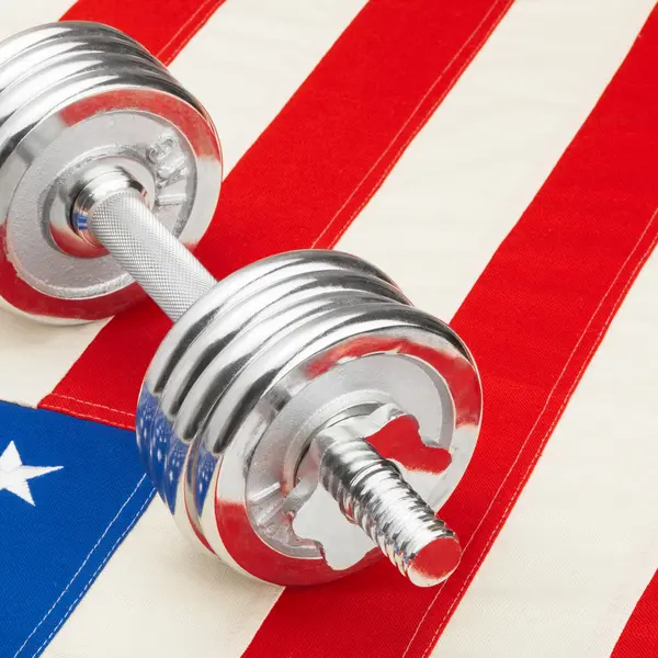 Metal dumbbells over US flag - studio closeup shot — Stock Photo, Image