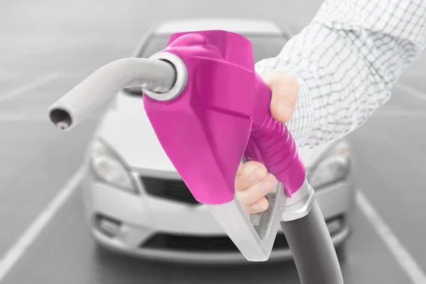 Růžová barva palivové čerpadlo zbraň v ruce s autem na pozadí — Stock fotografie
