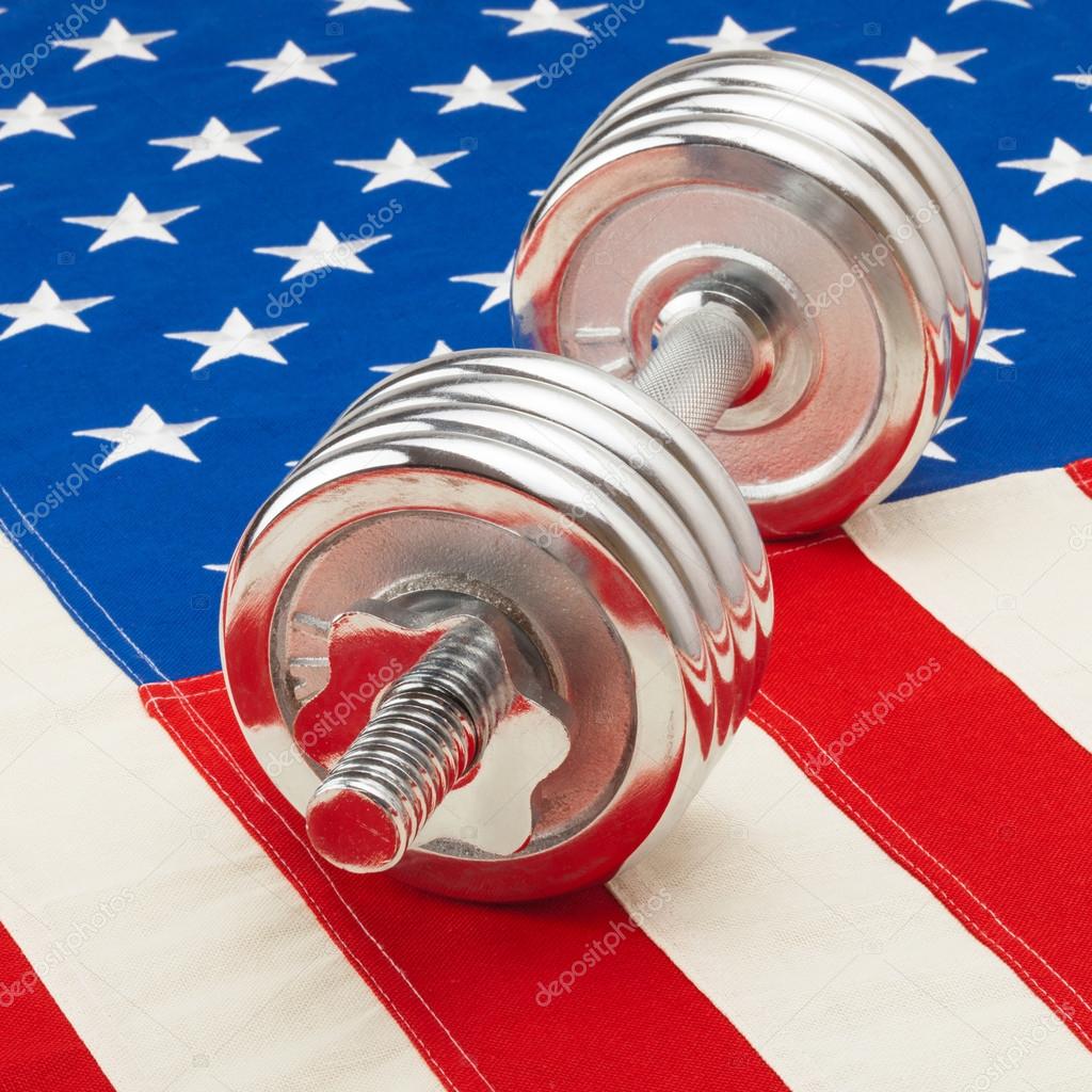 Shiny dumbbell over US flag as symbol of healthy life style - studio shot