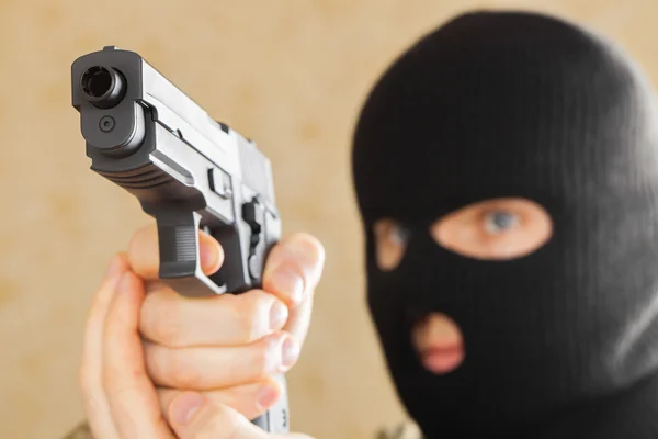 Hombre en máscara negra sosteniendo la pistola y listo para usarlo —  Fotos de Stock