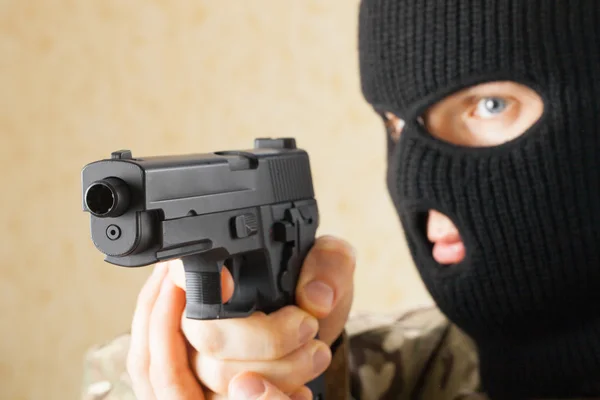 Omul cu mască neagră ţinând arma înaintea lui — Fotografie, imagine de stoc