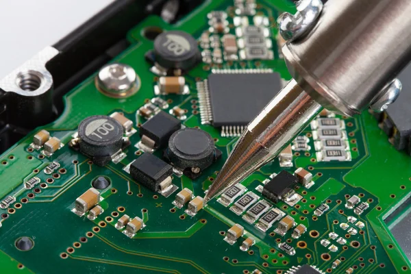 Studio shot of soldering iron and microcircuit — Stock Photo, Image