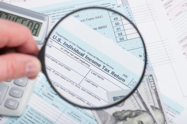 Formulário de imposto com lupa calculadora e dólares — Fotografia de Stock
