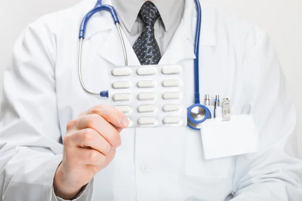 Doctor holdling pills in hand - studio shot — Stock Photo, Image