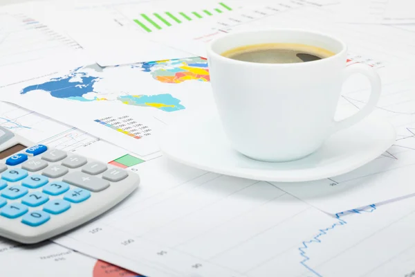 Tazza di caffè e calcolatore sopra grafici finanziari — Foto Stock