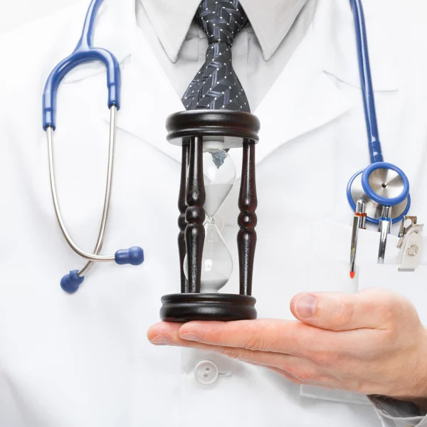 Doctor with hourglass in hand - studio shot — Stock Photo, Image