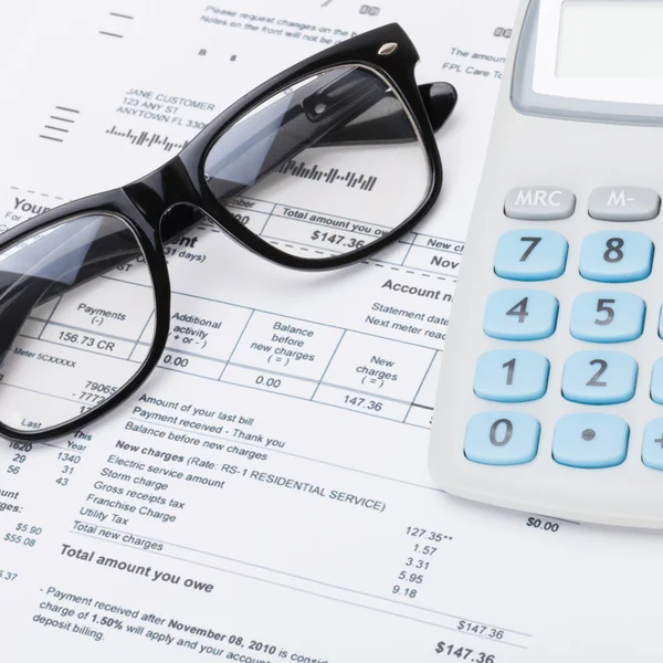 Calculator and glasses with utility bill under it - studio shot — Stock Photo, Image