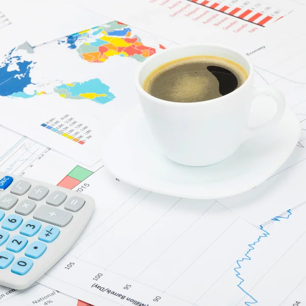 Tazza di caffè e calcolatore sopra grafici finanziari - colpo dello studio — Foto Stock