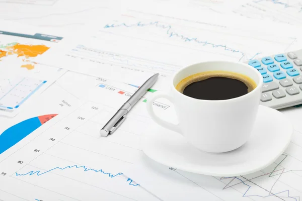 Coffee cup and calculator over world map and some financial charts — Stock Photo, Image