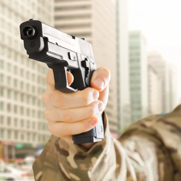 Hombre en ciudad sosteniendo la pistola en su mano — Foto de Stock