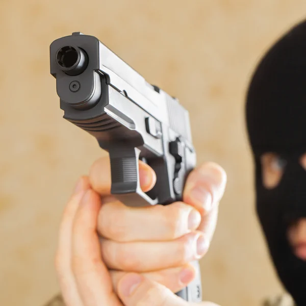 Omul cu masca neagra tinand arma si gata sa o foloseasca - studio shot — Fotografie, imagine de stoc