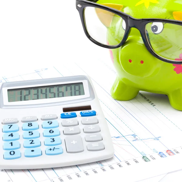 Stock market charts with piggy bank and calculator over it - studio shot — Stock Photo, Image