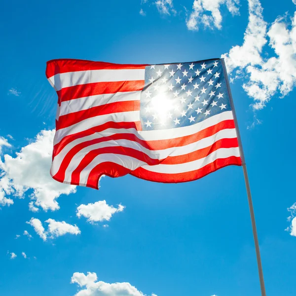 U.S. flag with cumulus clouds and blue sky on background — Stock Photo, Image