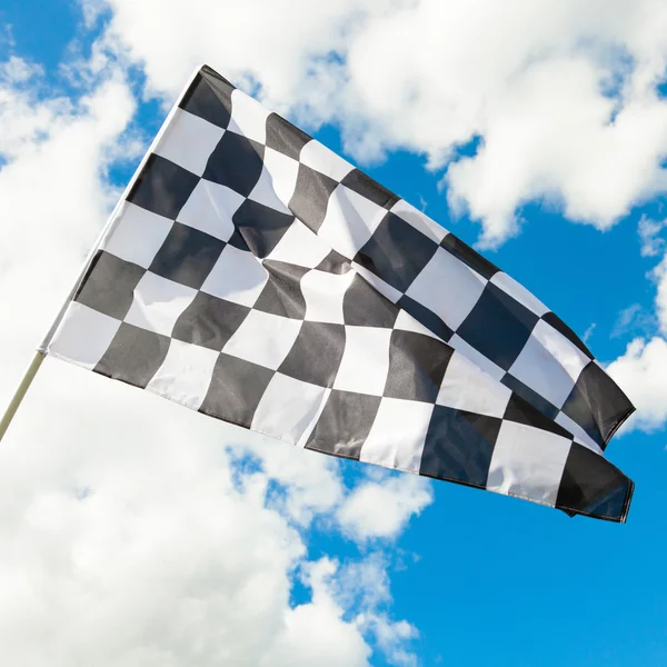 Neat checkered flag waving in the wind - clouds on background — Stock Photo, Image