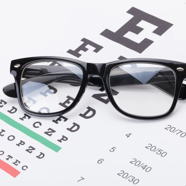 Tabla de prueba de vista y gafas sobre él - cerca de toma — Foto de Stock