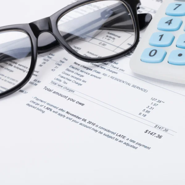 Акуратний калькулятор з ручкою, окулярами та рахунком за комунальні послуги - крупним планом — стокове фото