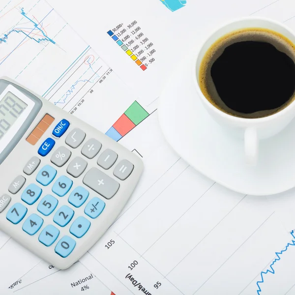 Coffee cup and calculator over world map and financial charts - close up shot — Stock Photo, Image