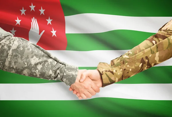 Men in uniform shaking hands with flag on background - Abkhazia — Stock Photo, Image