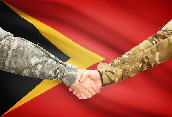 Men in uniform shaking hands with flag on background - East Timor — Stock Photo, Image