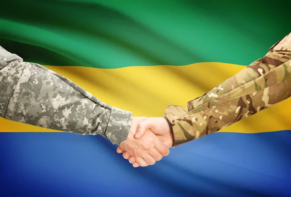 Hombres en uniforme de estrecharme la mano con la bandera en el fondo - Gabón — Foto de Stock