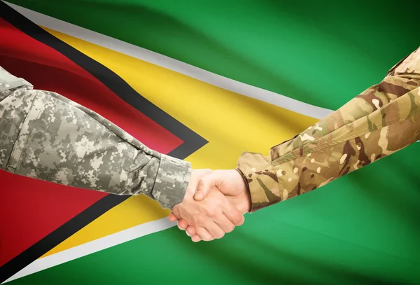 Men in uniform shaking hands with flag on background - Guyana — Stock Photo, Image