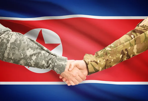 Men in uniform shaking hands with flag on background - North Korea — Stock Photo, Image