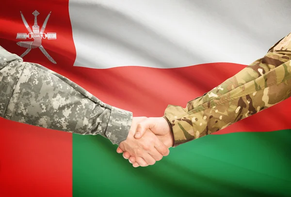 Men in uniform shaking hands with flag on background - Oman — Stock Photo, Image