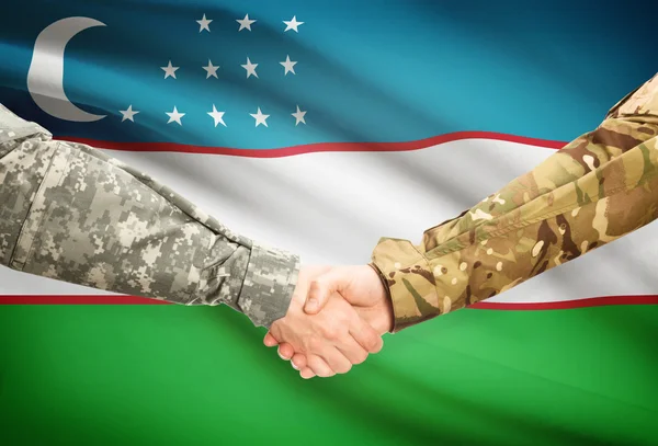 Men in uniform shaking hands with flag on background - Uzbekistan — Stock Photo, Image