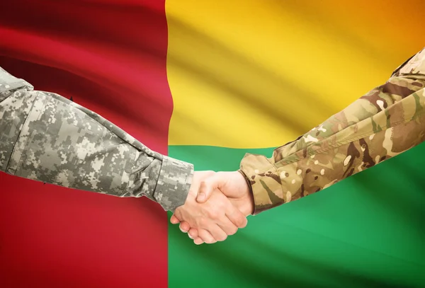 Homens de uniforme, cumprimentando-se com a bandeira no fundo - Guiné-Bissau — Fotografia de Stock