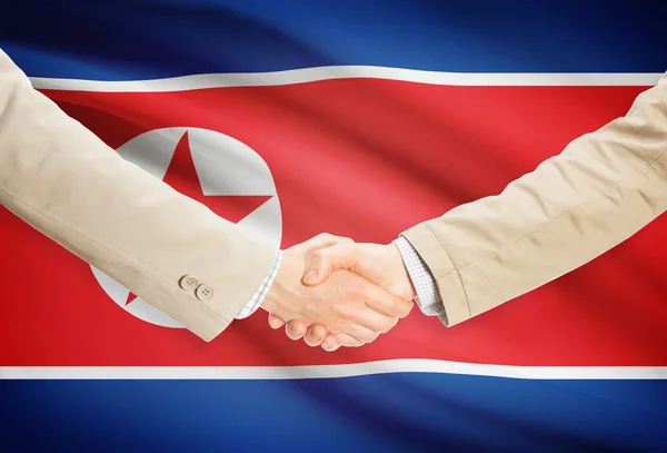 Aperto de mão de empresários com bandeira no fundo - Coreia do Norte — Fotografia de Stock