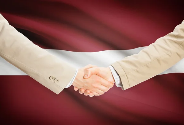 Unternehmer-Handshakes mit Flagge auf Hintergrund - Lettland — Stockfoto