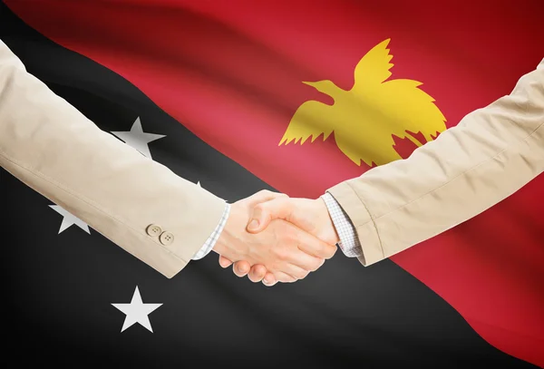 Apretón de manos de empresarios con bandera sobre fondo - Papua Nueva Guinea —  Fotos de Stock