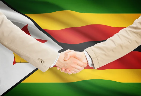 Apretón de manos de empresarios con bandera sobre fondo - Zimbabwe — Foto de Stock