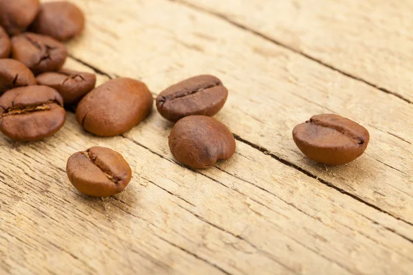 Coffee beans on old wooden table - close up studio shot — Stock Photo, Image