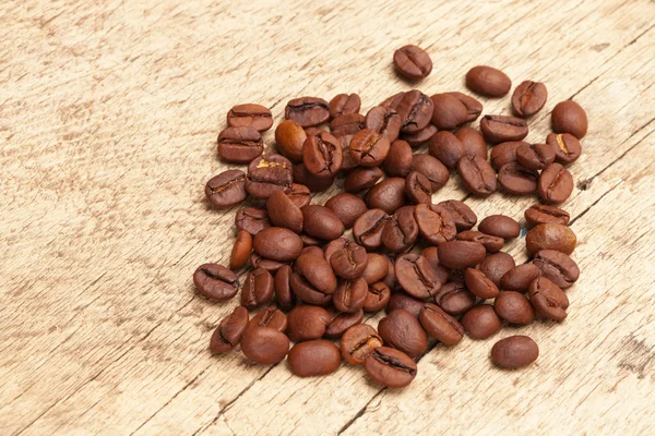 Coffee beans over old wooden table — Stock Photo, Image