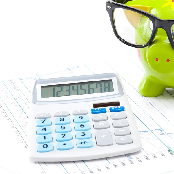 Market charts with piggy bank and calculator over it - close up — Stock Photo, Image