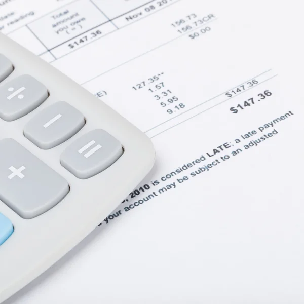 Calculator with utility bill under it - close up studio shot — Stock Photo, Image