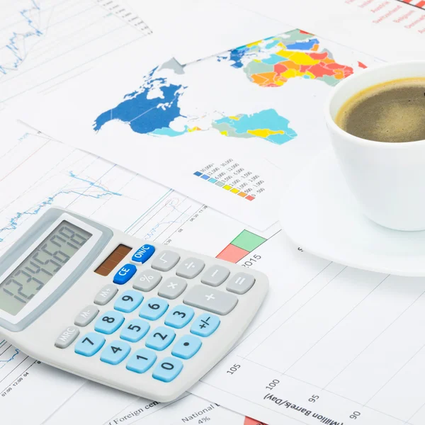 Tazza di caffè e calcolatore sopra grafici finanziari - Chiuda sul colpo — Foto Stock