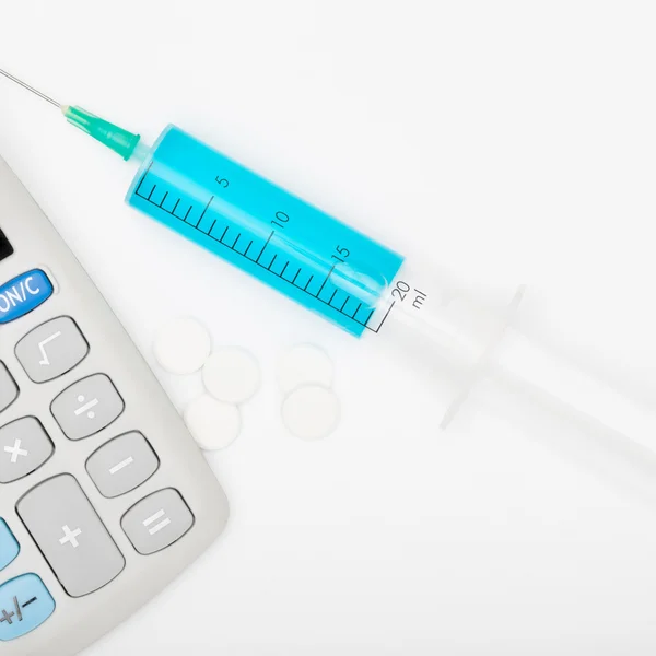 Calculator and a syringe - close up shot — Stock Photo, Image