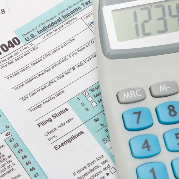 US 1040 Tax Form and calculator over it - close up — Stock Photo, Image