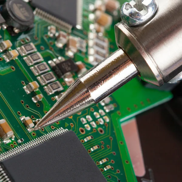 Soldering iron and microcircuit - closeup shot — Stock Photo, Image