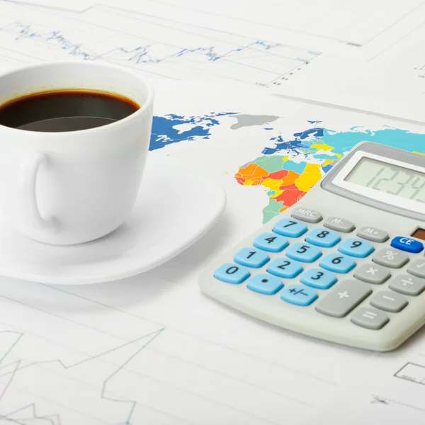Coffee cup and calculator over world map and some financial chart - close up — Stock Photo, Image