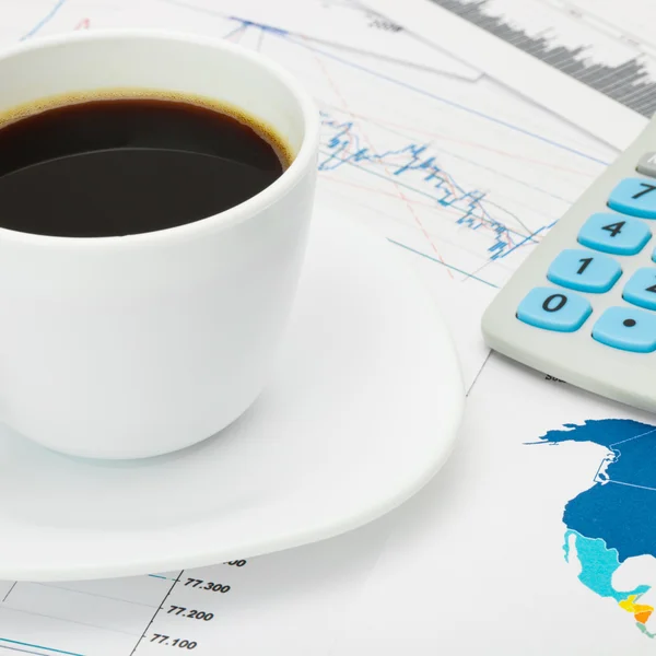 Coffee cup and calculator over world map and some financial chart - close up — Stock Photo, Image