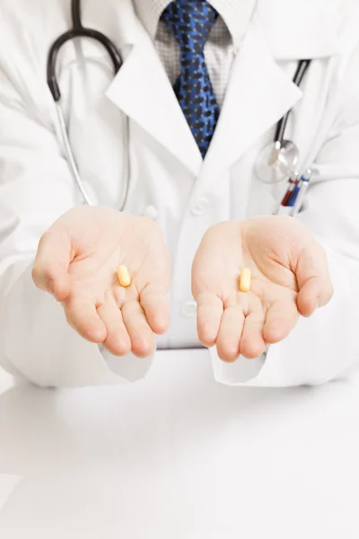 Doctor holding one pill on each palm - studio shot — Fotografia de Stock